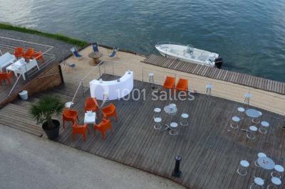 Façade éclairée d'un bâtiment nommé ’Le Yacht’ de nuit, avec des lumières bleues et un espace extérieur aménagé.