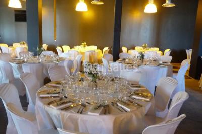 Façade éclairée d'un bâtiment nommé ’Le Yacht’ de nuit, avec des lumières bleues et un espace extérieur aménagé.