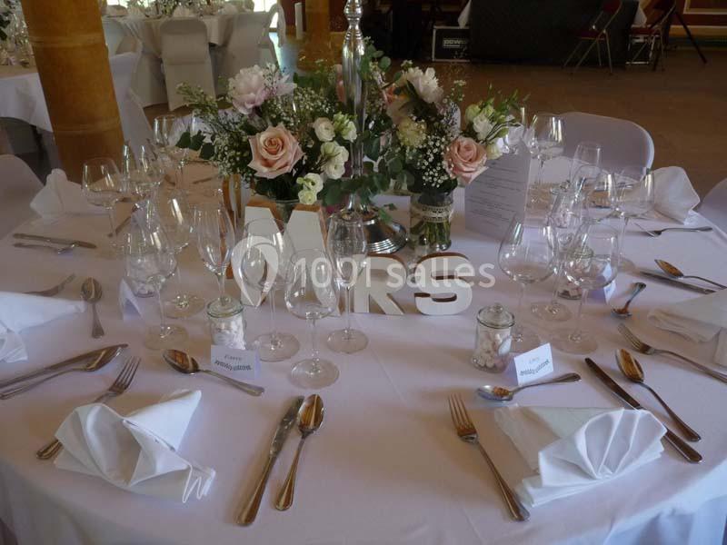 Table de réception élégamment dressée avec des fleurs, des verres, des couverts et des lettres décoratives ’MRS’.
