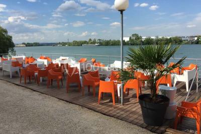 Façade éclairée d'un bâtiment nommé ’Le Yacht’ de nuit, avec des lumières bleues et un espace extérieur aménagé.