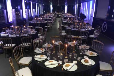 Façade éclairée d'un bâtiment nommé ’Le Yacht’ de nuit, avec des lumières bleues et un espace extérieur aménagé.