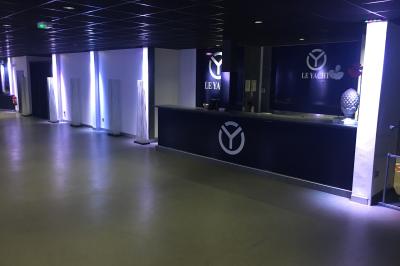 Façade éclairée d'un bâtiment nommé ’Le Yacht’ de nuit, avec des lumières bleues et un espace extérieur aménagé.