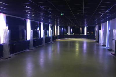 Façade éclairée d'un bâtiment nommé ’Le Yacht’ de nuit, avec des lumières bleues et un espace extérieur aménagé.