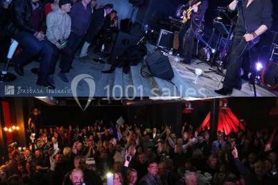 Façade éclairée d'un bâtiment nommé ’Le Yacht’ de nuit, avec des lumières bleues et un espace extérieur aménagé.