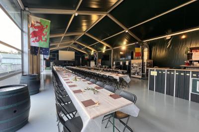 Deux hommes en tenue de rugby bleue simulent une action de jeu dans une salle éclairée avec des chaises vides.