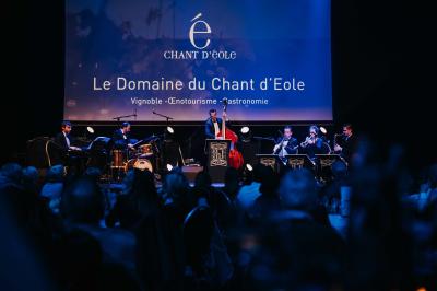 Éoliennes dans un paysage rural avec des vignes au premier plan et un ciel nuageux en arrière-plan.