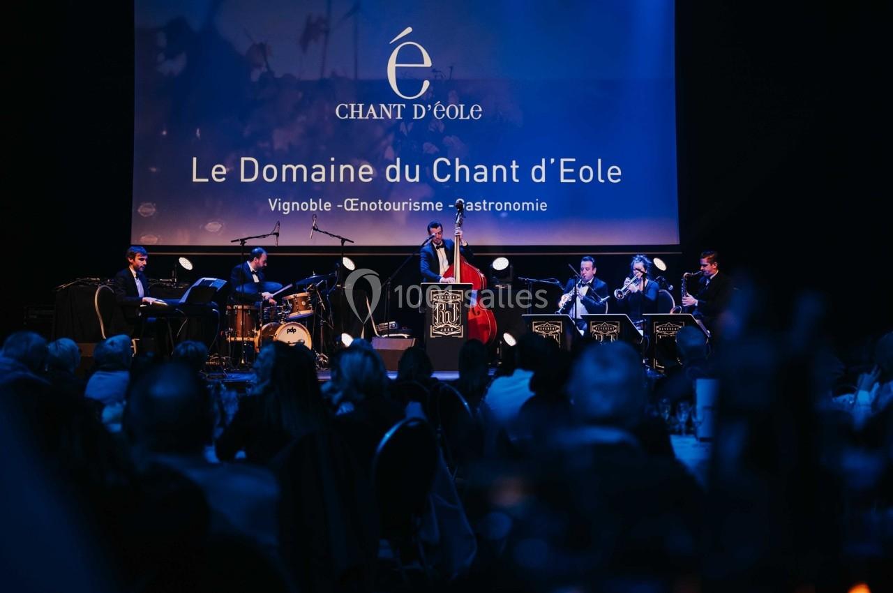 Un groupe de musiciens joue sur scène devant un public, avec une projection visuelle en arrière-plan.