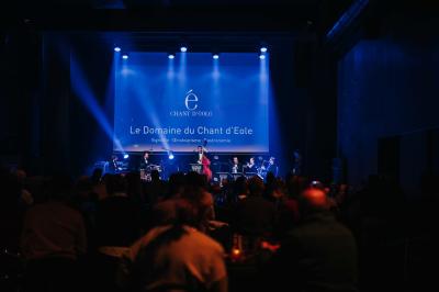 Éoliennes dans un paysage rural avec des vignes au premier plan et un ciel nuageux en arrière-plan.