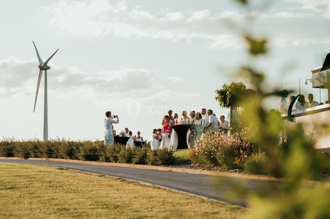 Un groupe de personnes rassemblées en extérieur près d'un bâtiment, avec une éolienne visible en arrière-plan.