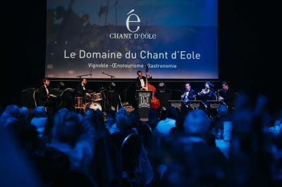 Rangées de chaises noires alignées dans une salle lumineuse avec une table en bois au premier plan.