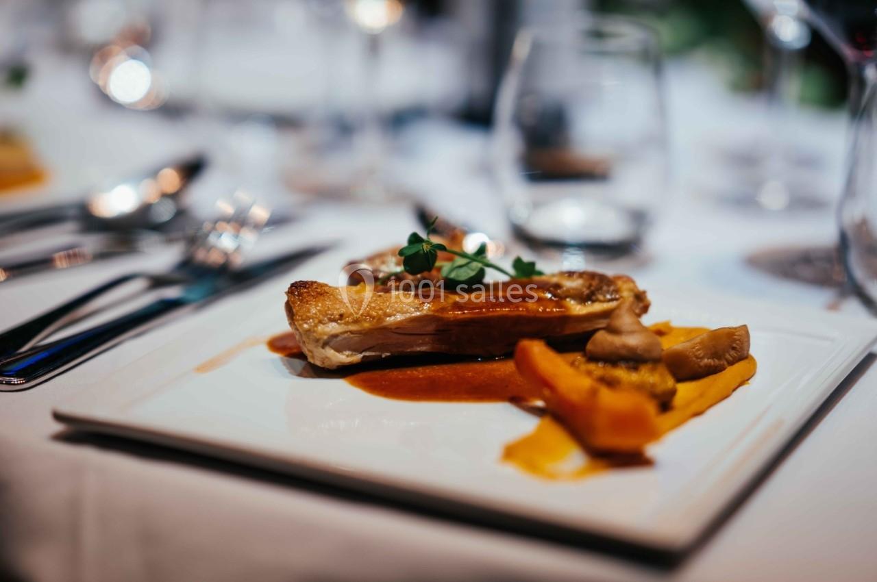 Assiette gastronomique avec viande grillée, purée de carottes, champignons et sauce, servie sur une table élégamment dressée.