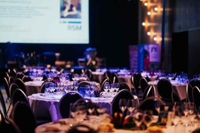 Rangées de chaises noires alignées dans une salle lumineuse avec une table en bois au premier plan.