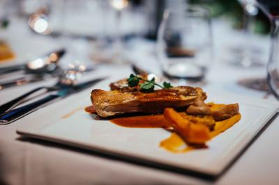 Terrasse moderne avec tables et parasols, entourée de pelouse, sous un ciel bleu dégagé.