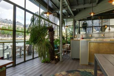 Bâtiment flottant moderne avec façade végétalisée, accessible par une passerelle en bois, amarré le long d'un quai pavé.