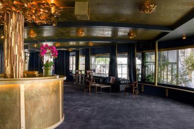 Bâtiment flottant moderne avec façade végétalisée, accessible par une passerelle en bois, amarré le long d'un quai pavé.