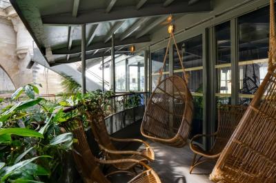 Bâtiment flottant moderne avec façade végétalisée, accessible par une passerelle en bois, amarré le long d'un quai pavé.