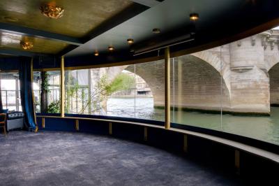 Bâtiment flottant moderne avec façade végétalisée, accessible par une passerelle en bois, amarré le long d'un quai pavé.