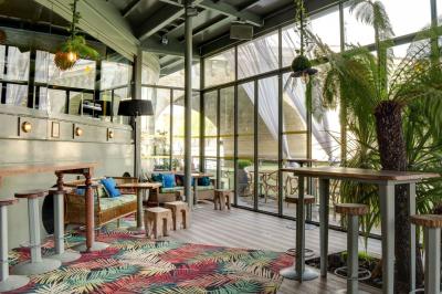 Bâtiment flottant moderne avec façade végétalisée, accessible par une passerelle en bois, amarré le long d'un quai pavé.