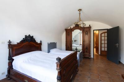 Salle de bain lumineuse avec baignoire, colonnes décoratives, miroir mural et carrelage clair.