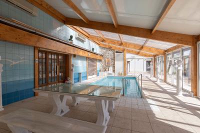 Salle de bain lumineuse avec baignoire, colonnes décoratives, miroir mural et carrelage clair.