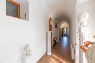 Salle de bain lumineuse avec baignoire, colonnes décoratives, miroir mural et carrelage clair.