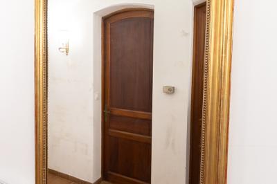Salle de bain lumineuse avec baignoire, colonnes décoratives, miroir mural et carrelage clair.
