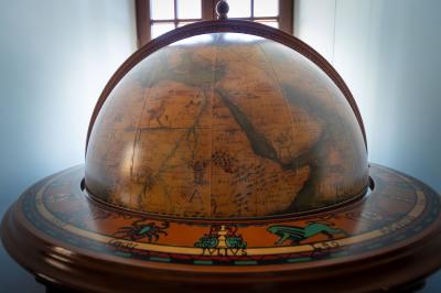 Salle de bain lumineuse avec baignoire, colonnes décoratives, miroir mural et carrelage clair.