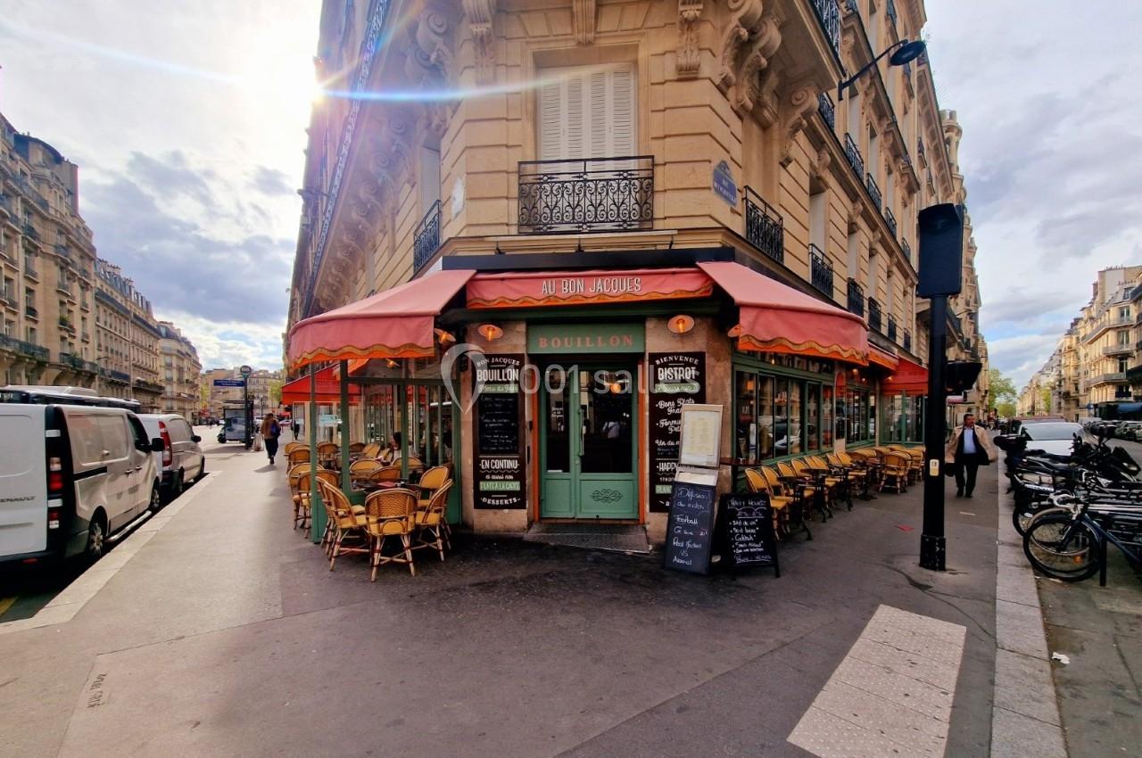 Façade d'un restaurant parisien avec terrasse, tables et chaises en extérieur, situé à l'angle de deux rues.