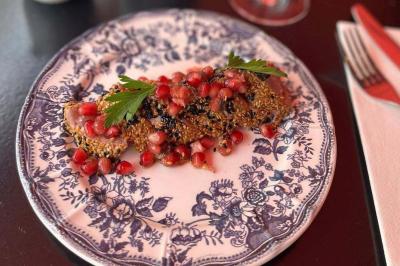 Jarret d'agneau braisé servi sur une purée crémeuse avec des morceaux de carottes, présenté dans une assiette noire.