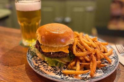 Jarret d'agneau braisé servi sur une purée crémeuse avec des morceaux de carottes, présenté dans une assiette noire.