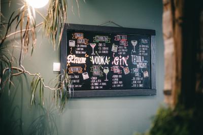 Bouteilles de bière variées alignées sur une étagère en bois devant un mur en pierre.