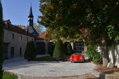 Clocher d'église avec horloge visible, entouré de bâtiments en briques et de végétation sous un ciel bleu.