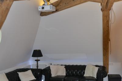 Clocher d'église avec horloge visible, entouré de bâtiments en briques et de végétation sous un ciel bleu.