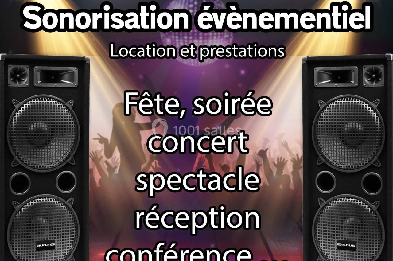 Deux enceintes audio devant une scène illuminée avec silhouettes de personnes dansant en arrière-plan.