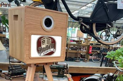 Boîtier en bois sur trépied avec un objectif, utilisé pour des événements, dans un espace décoré de vélos et objets vintage.