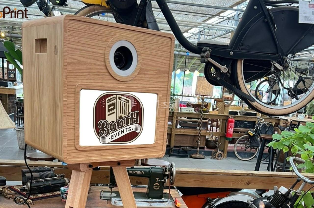 Boîtier en bois sur trépied avec un objectif, utilisé pour des événements, dans un espace décoré de vélos et objets vintage.