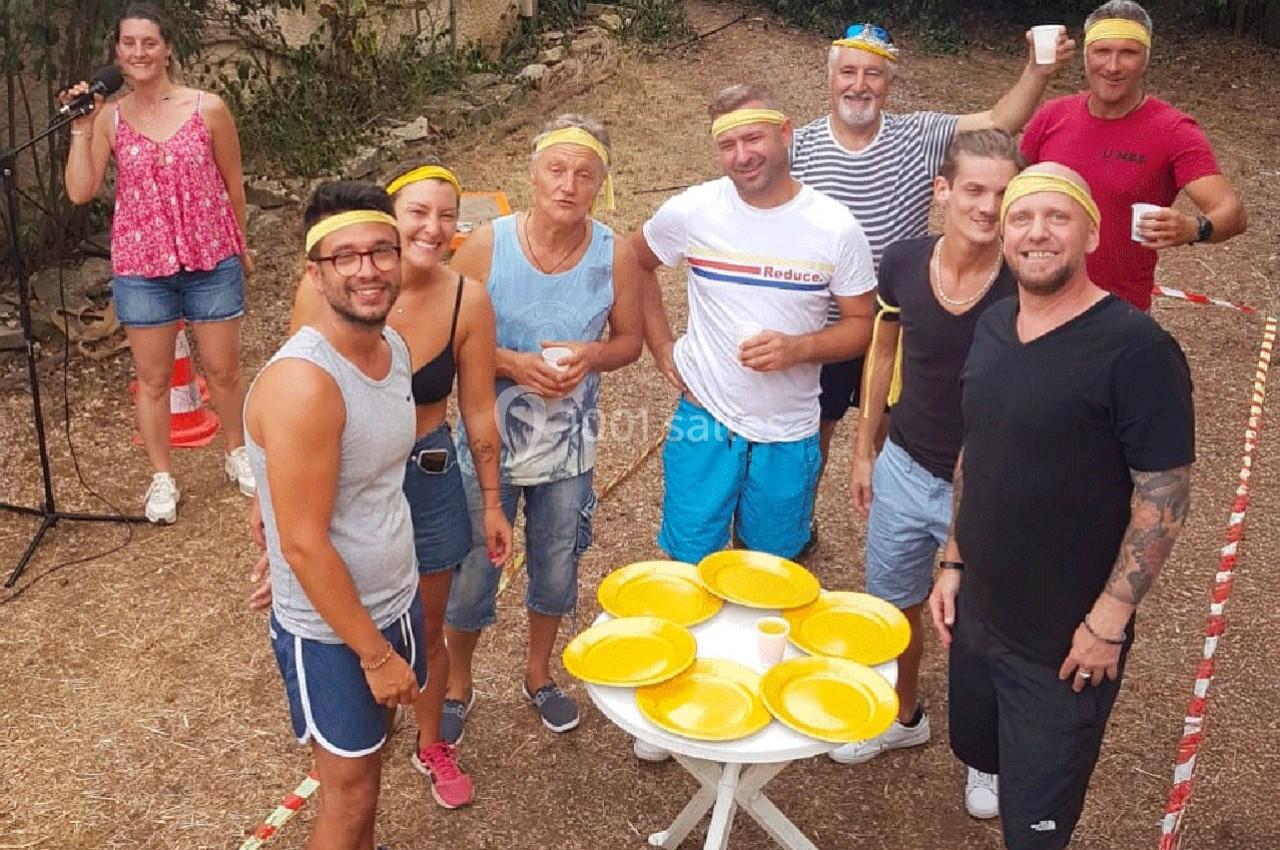 Un groupe de personnes souriantes portant des bandeaux jaunes, rassemblées autour d'une table avec des assiettes jaunes.