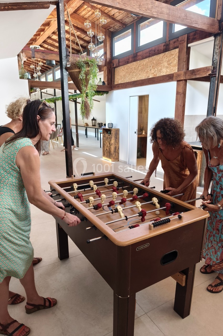 Quatre femmes jouent au baby-foot dans un espace lumineux avec une structure en bois et des plantes suspendues.