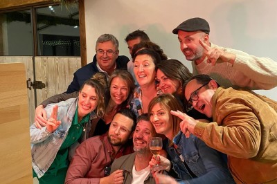 Des oies blanches se promènent dans un enclos herbeux, avec un arbre et une clôture en arrière-plan.