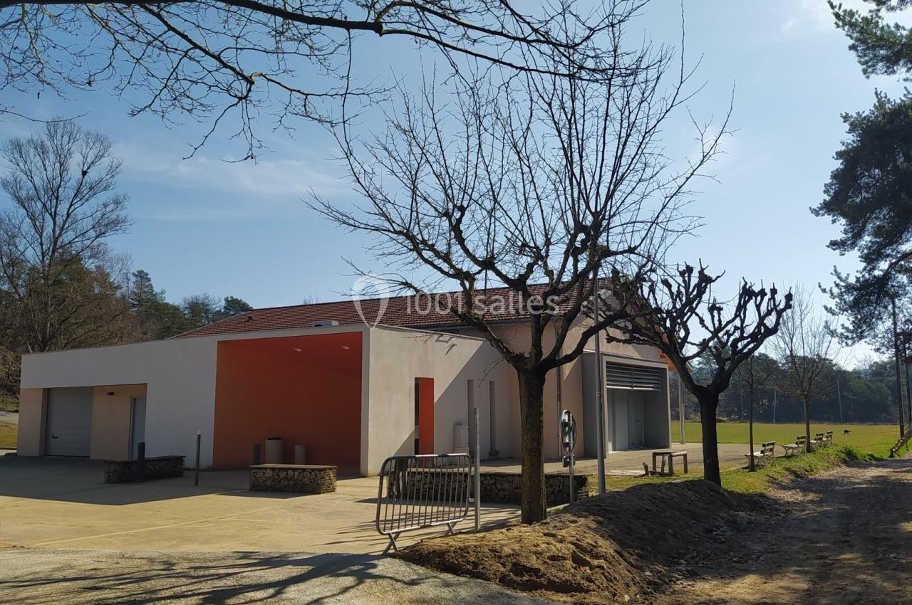 Bâtiment moderne avec toit rouge, entouré d'arbres sans feuilles, situé près d'un chemin et d'une pelouse.