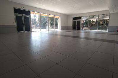 Douche moderne avec paroi vitrée, pommeau mural et lavabo blanc dans une salle de bain aux murs clairs.