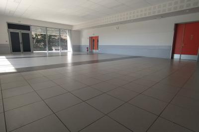 Douche moderne avec paroi vitrée, pommeau mural et lavabo blanc dans une salle de bain aux murs clairs.