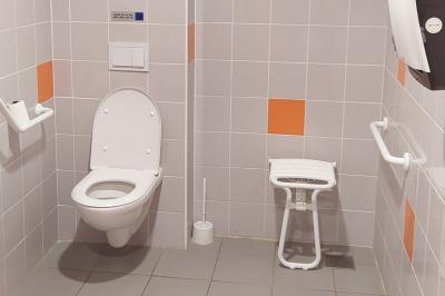 Douche moderne avec paroi vitrée, pommeau mural et lavabo blanc dans une salle de bain aux murs clairs.