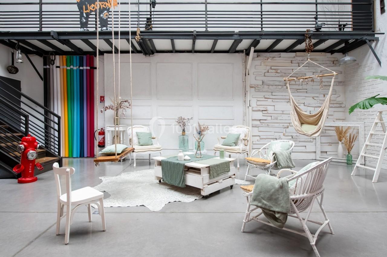 Espace lumineux avec mobilier en bois clair, fauteuils, balançoires et décorations dans un style bohème et industriel.