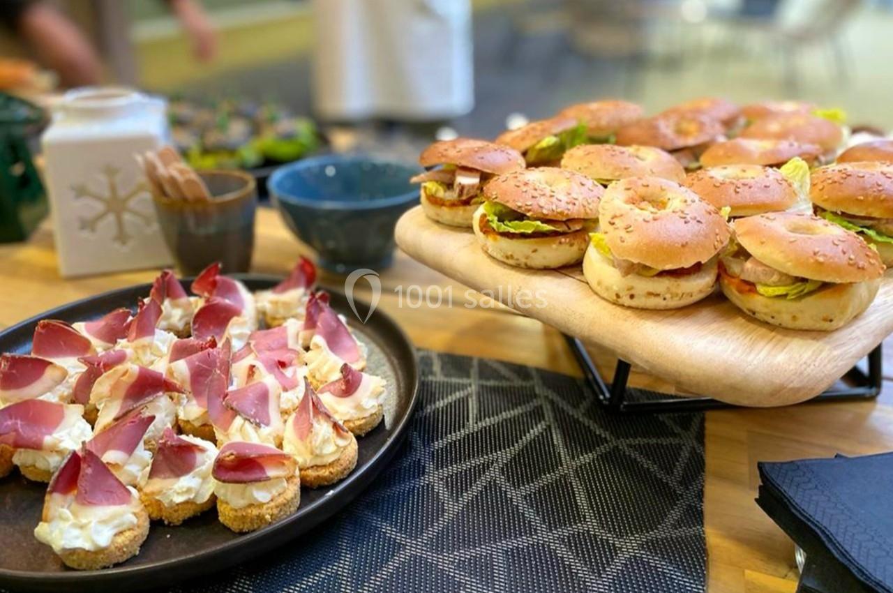 Plateau de mini-burgers et toasts au jambon et fromage disposés sur une table en bois avec des nappes noires.