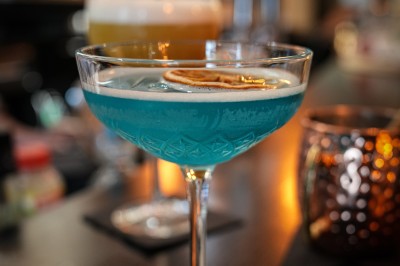 Plusieurs Citroën 2CV colorées alignées sur un parking ensoleillé.