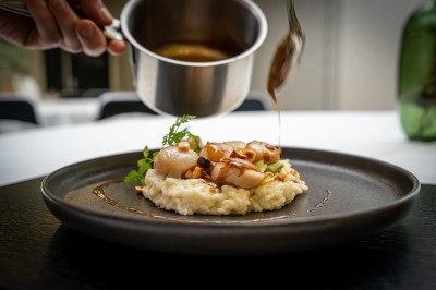 Plusieurs Citroën 2CV colorées alignées sur un parking ensoleillé.