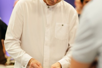 Plusieurs Citroën 2CV colorées alignées sur un parking ensoleillé.