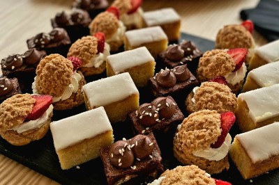 Plusieurs Citroën 2CV colorées alignées sur un parking ensoleillé.