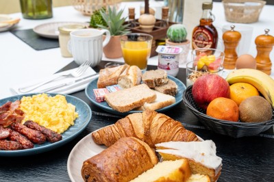 Plusieurs Citroën 2CV colorées alignées sur un parking ensoleillé.